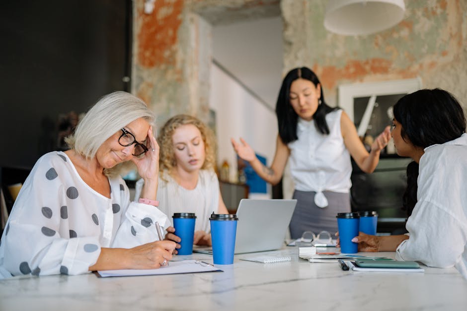 A business meeting with diverse women discussing and expressing emotions at a table