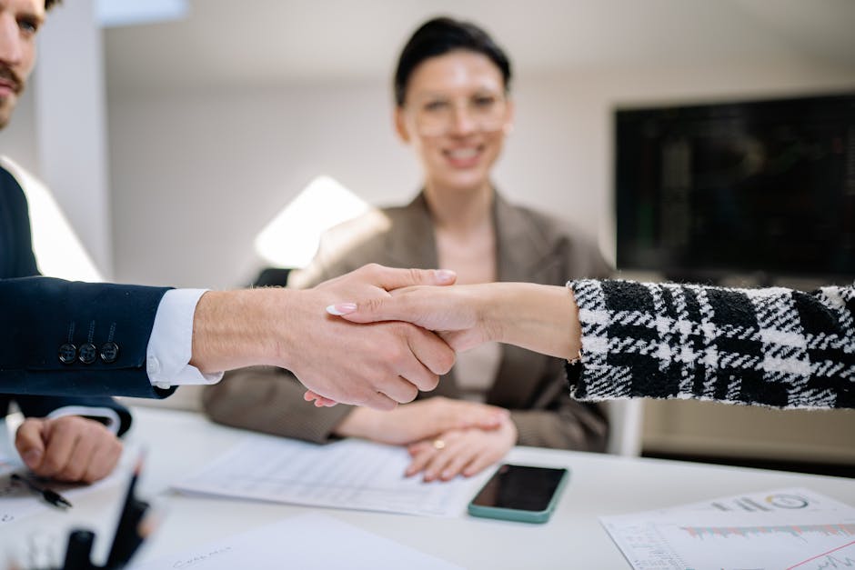 Professional handshake sealing a business deal with colleagues observing