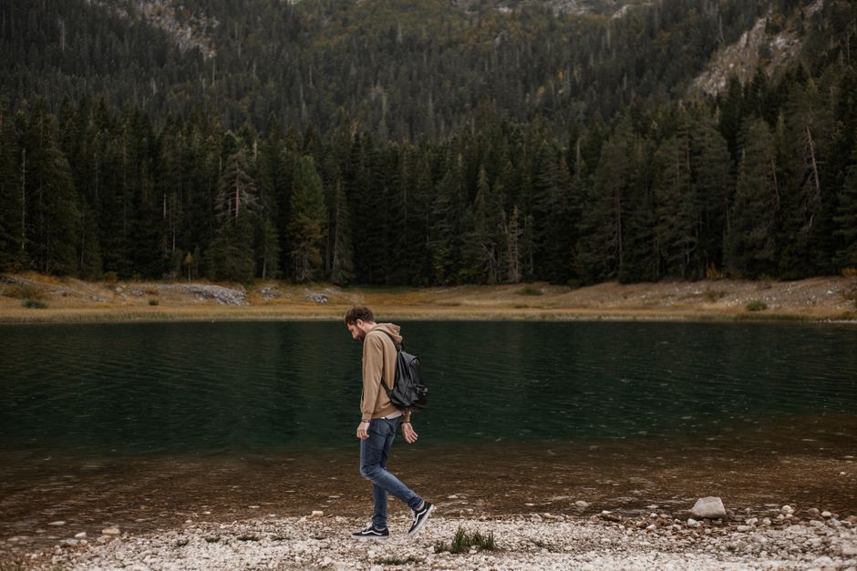 A lone man enjoys a walk by a tranquil mountain lake