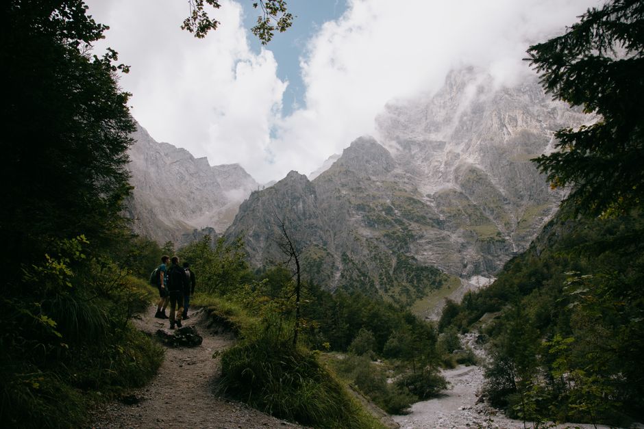Group of backpackers walking on route pathway with river stream against marvellous mountains in snow